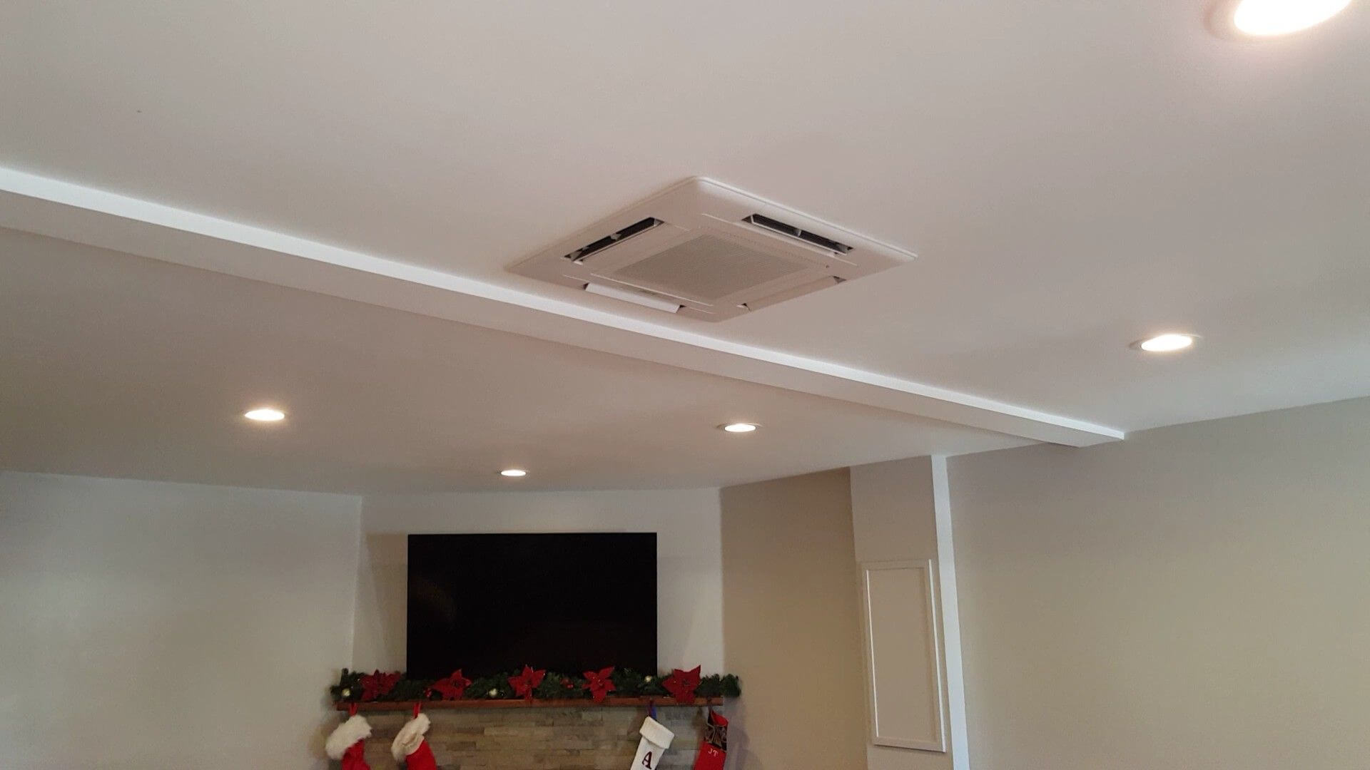 Ceiling-mounted cassette air conditioner in a room, providing 360-degree airflow for uniform cooling and heating.