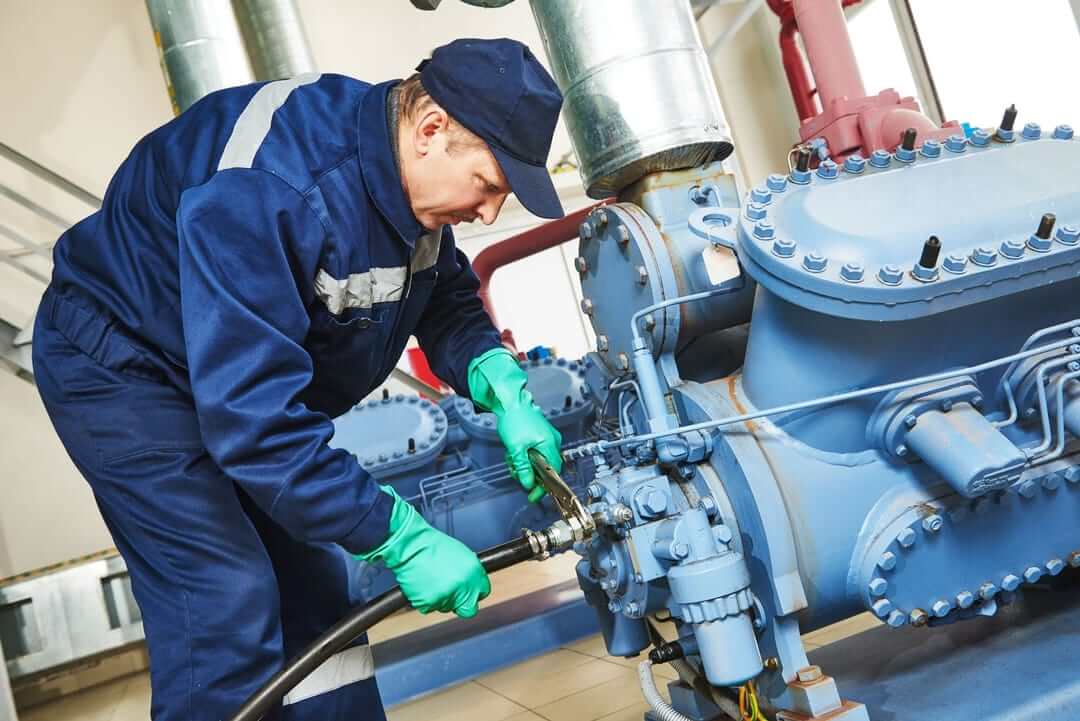 Technician performing refrigeration maintenance on industrial equipment