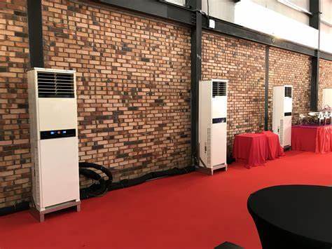 Floor-standing air conditioning units against a brick wall in a room