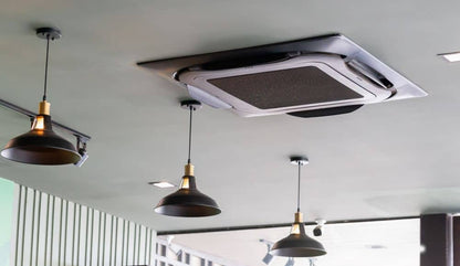 Ceiling-mounted cassette air conditioner installation in a commercial space with modern lighting fixtures.