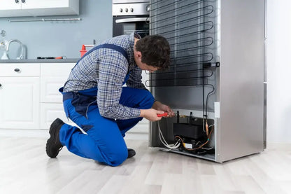 Technician repairing refrigerator in kitchen for refrigeration breakdowns and 24/7 call-out service in Norwich, Frostbite Services